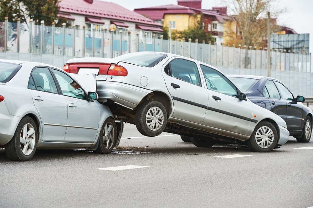 Three-car collision showing a multi-car pileup on a city street, with visible vehicle damage from a rear-end crash—common in chain-reaction accidents.