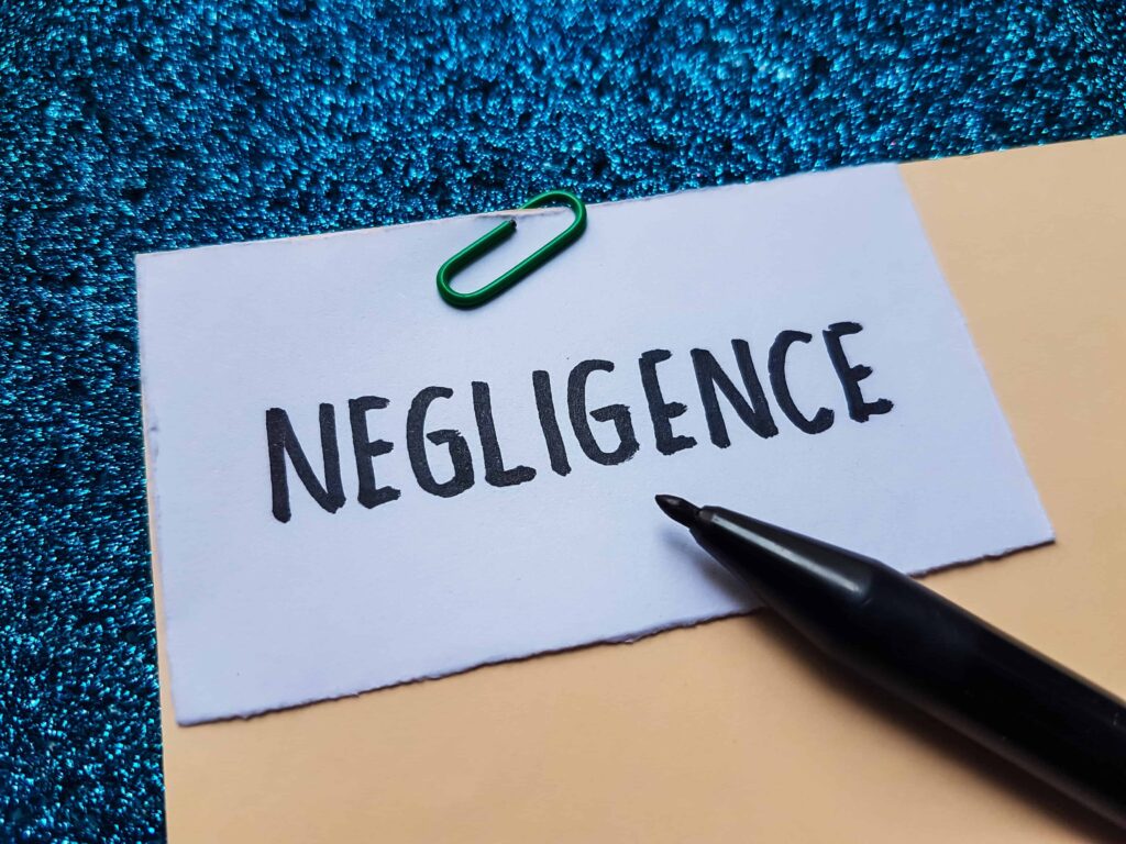 Paper with the word &lsquo;Negligence&rsquo; written on it next to a pen and paperclip.