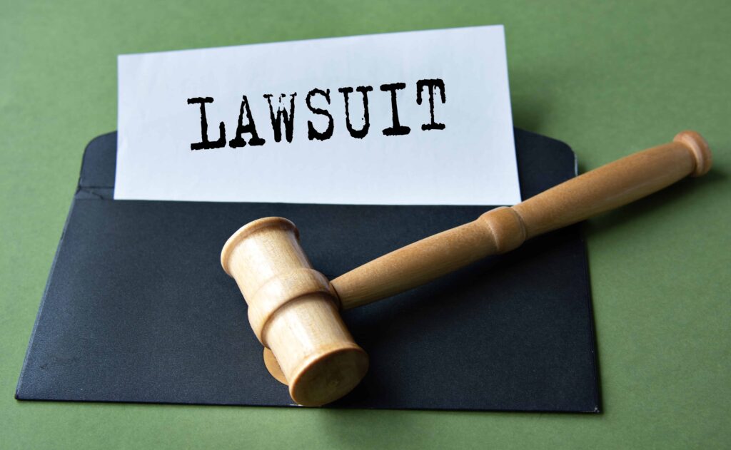 Legal document labeled &lsquo;Lawsuit&rsquo; with judge&rsquo;s gavel on top of a black folder, symbolizing legal action and court proceedings.