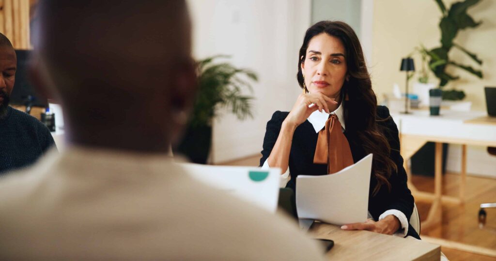 Female professional attentively listening during a business meeting and reviewing documents.