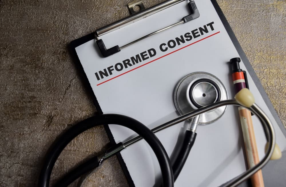 Concept of informed consent write on clipboard isolated on Wooden Table.
